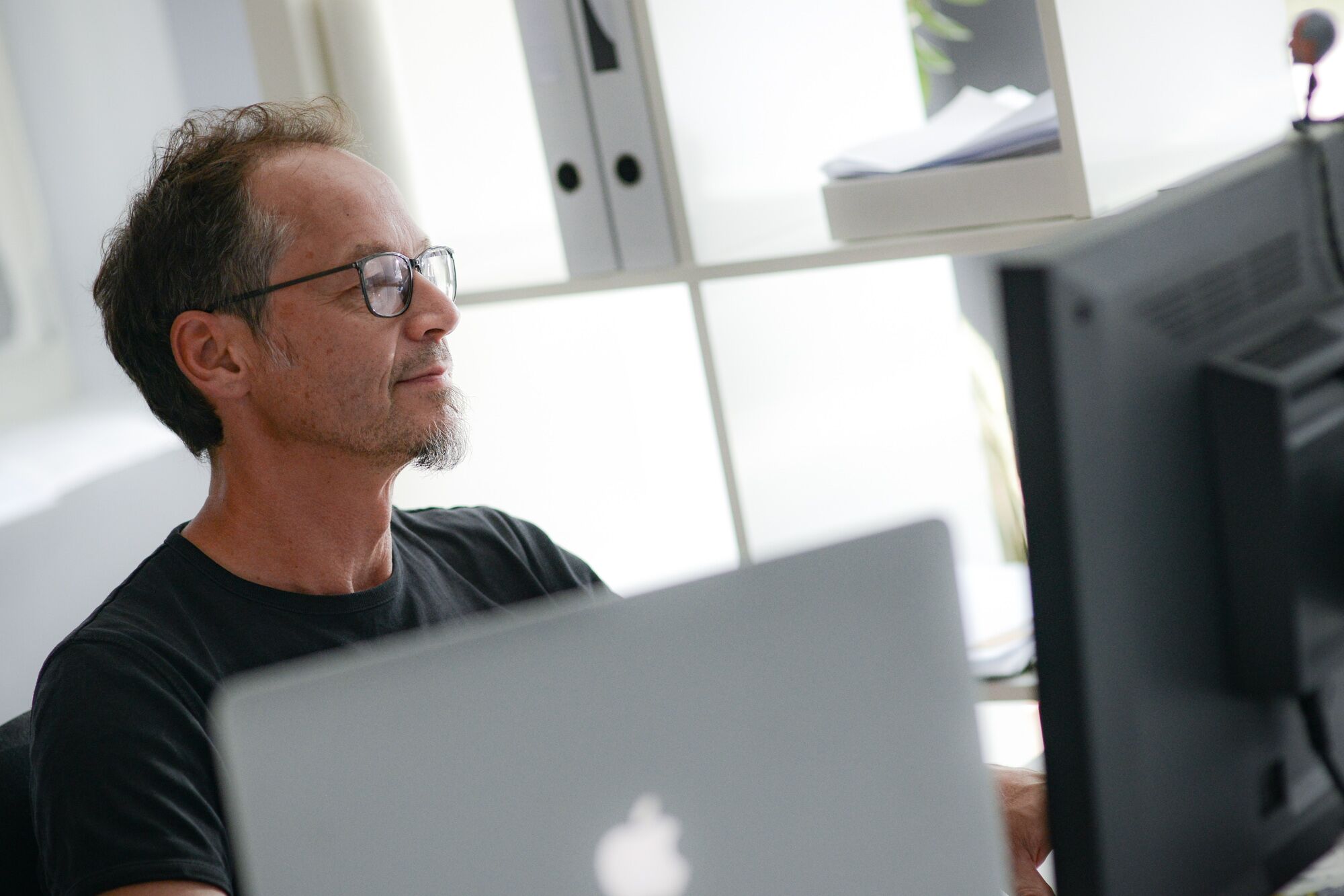 Sam, Gründer der nuun gmbh, konzentriert am Bildschirm im Büro – Webentwicklung und Webdesign